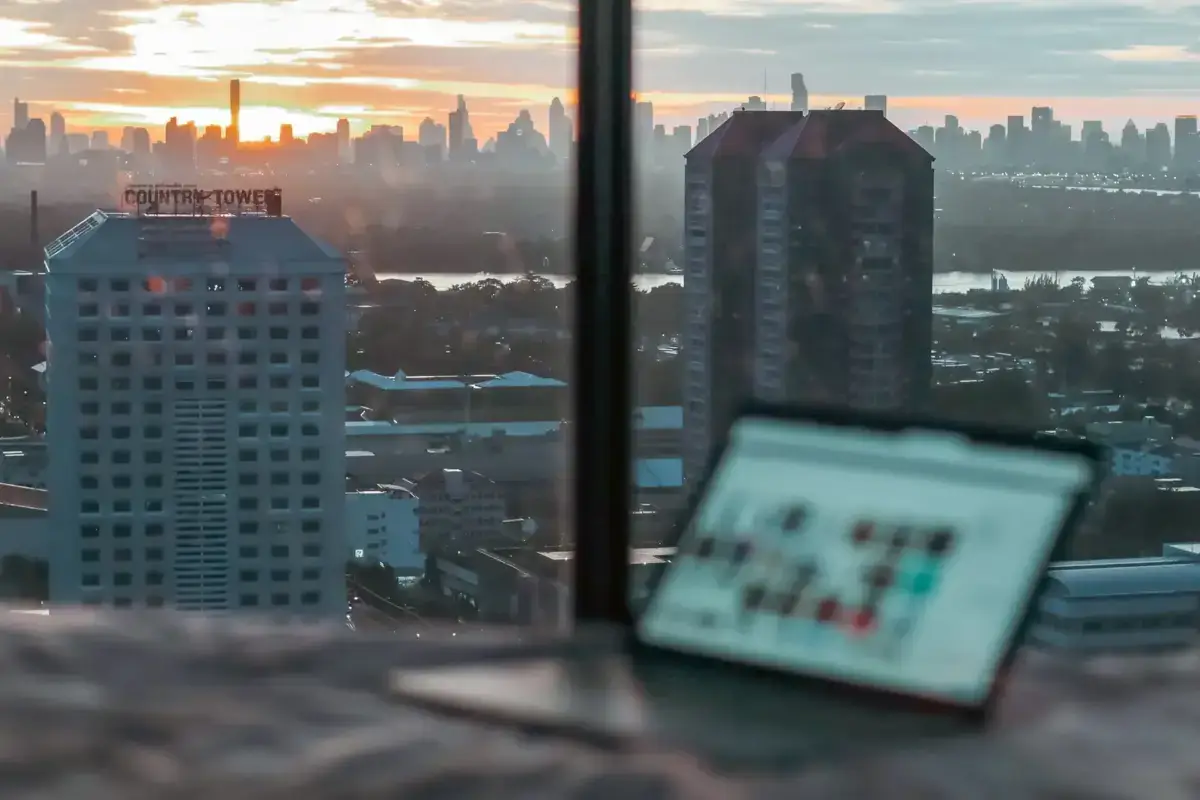 Passport and travel documents on windowsill overlooking city skyline at sunrise, capturing the essence of business travel and urban destinations.