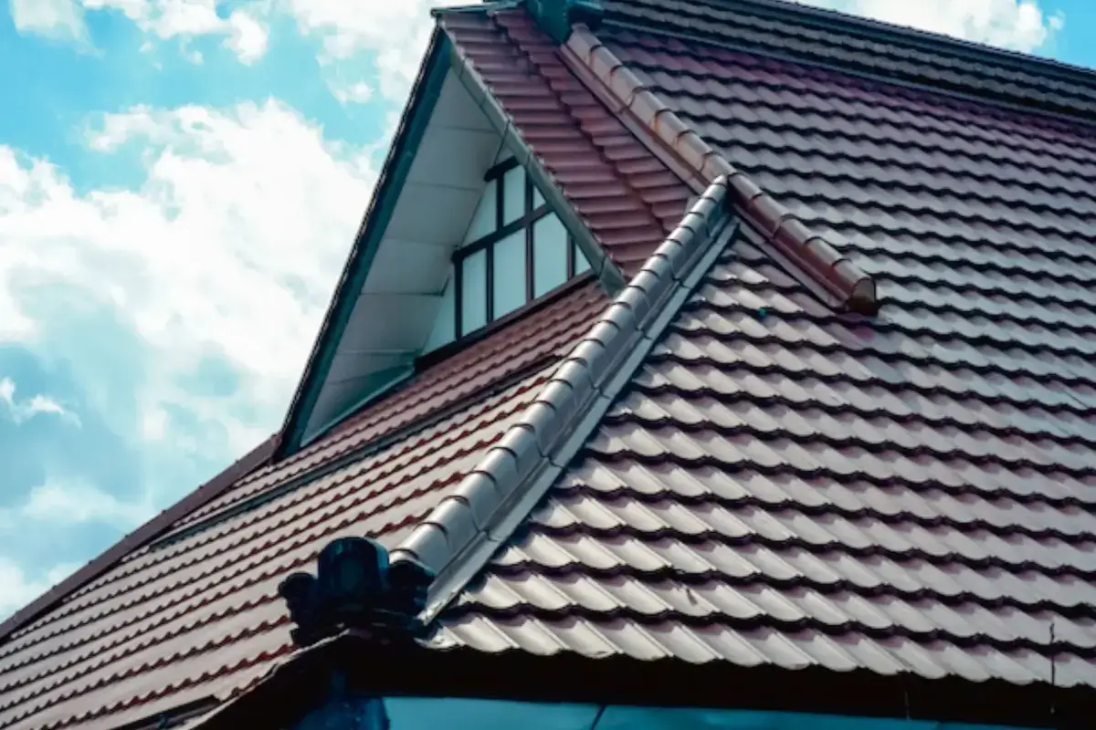 Traditional Japanese-style tile rooftops with dark brown curved tiles and white trim against a bright blue sky with white clouds.