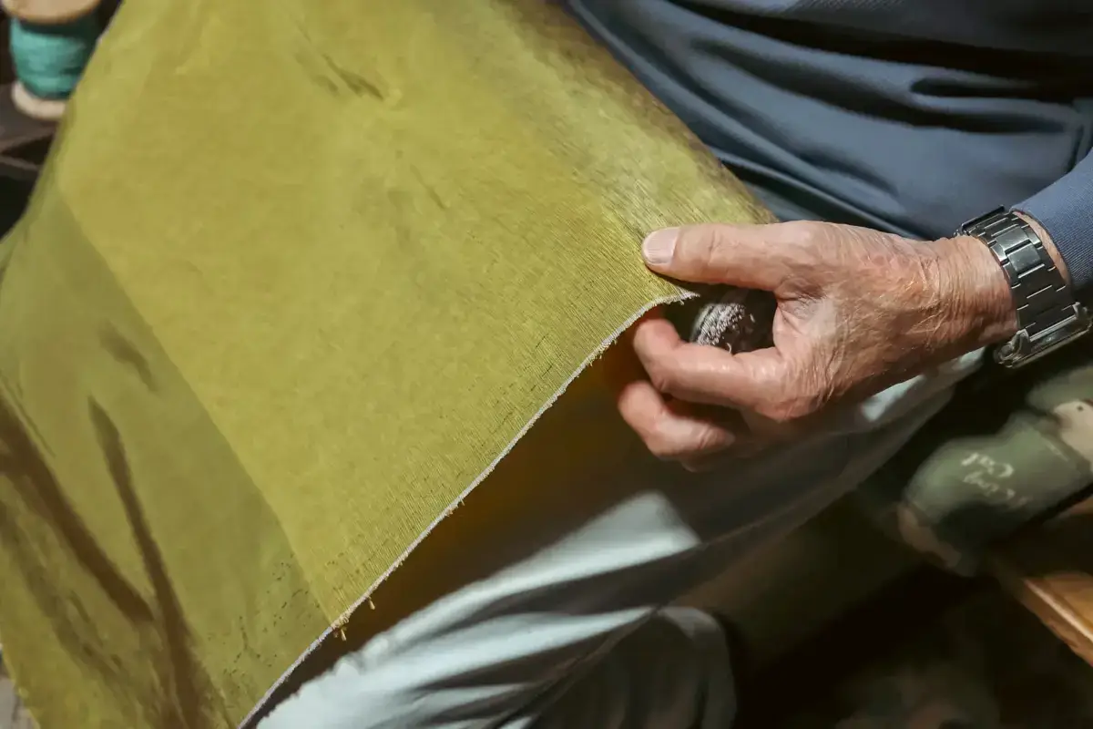 Artisan hand weaving golden-yellow silk fabric on a traditional loom in Hachijojima, showcasing the island's renowned textile craftsmanship.