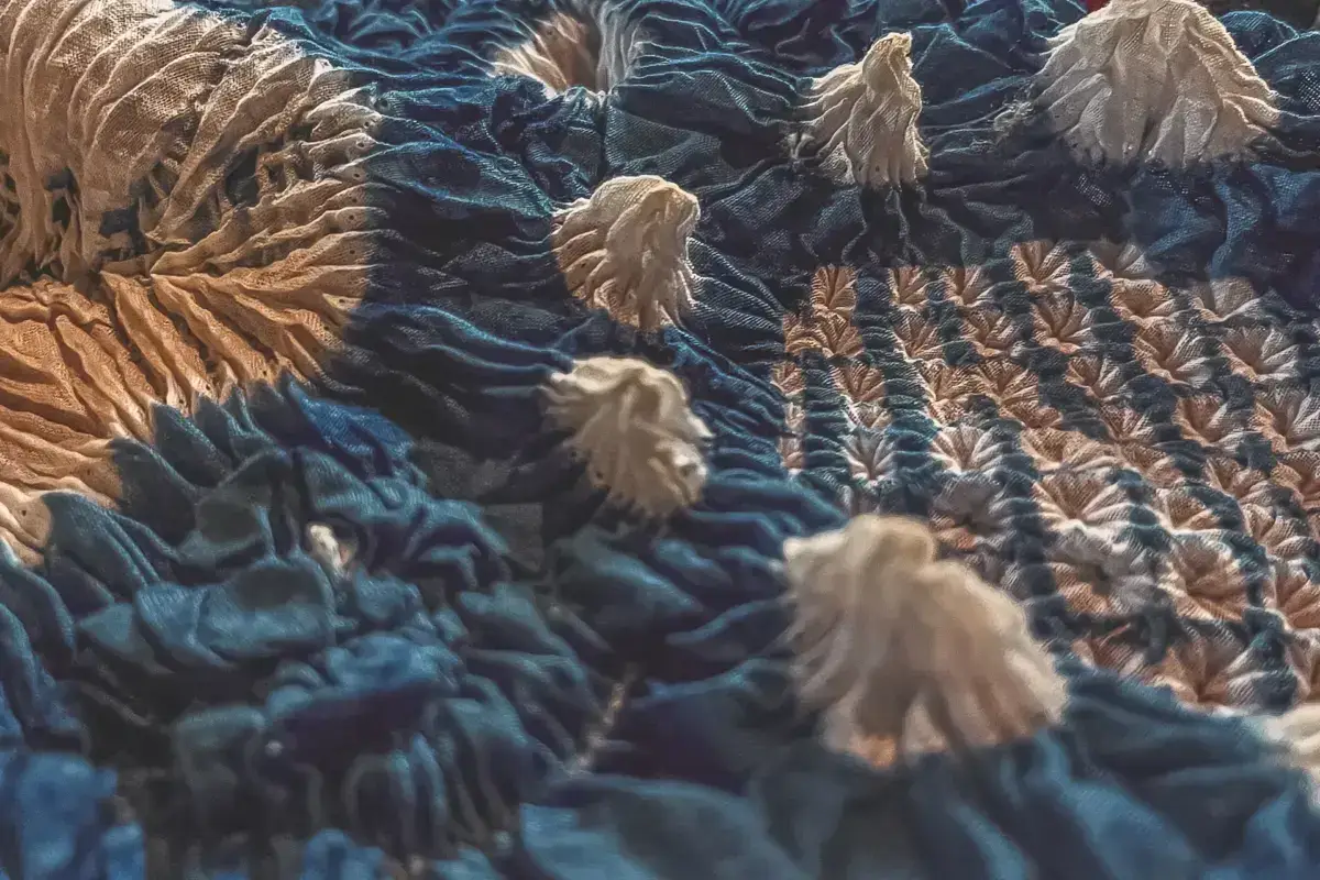 Traditional Japanese embroidered textile featuring cranes, pine trees, and waves in gold and beige thread on a deep blue silk fabric, showcasing Aichi's intricate artisan craftsmanship.