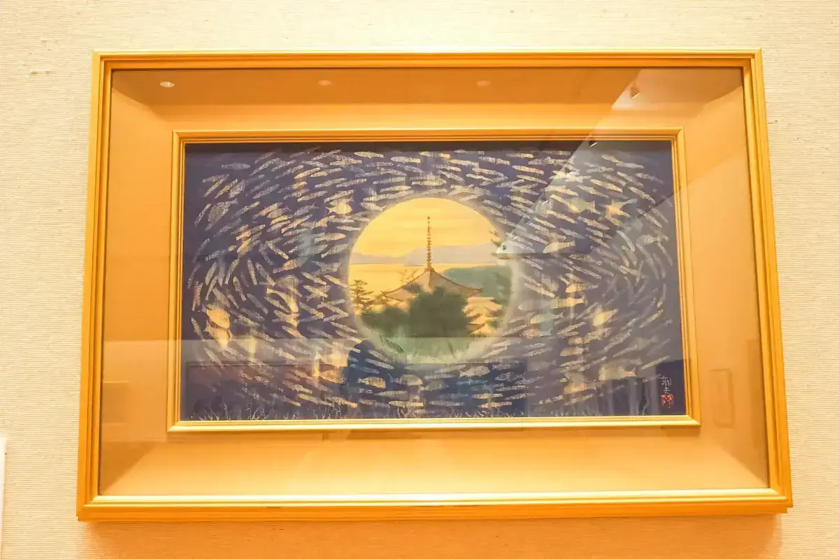 Framed Japanese artwork depicting a pagoda silhouette centered within a circular vortex of blue and gold brushstrokes against a warm sunset sky.
