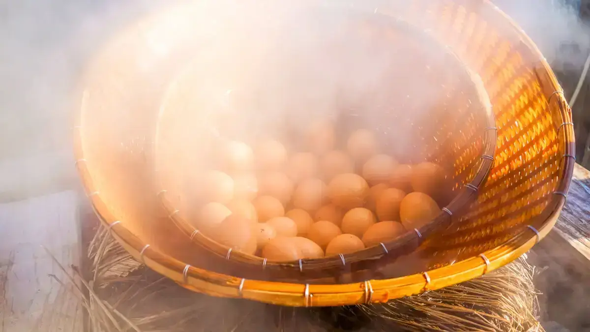 Fresh eggs in a traditional bamboo basket bathed in warm sunlight, with steam rising from a hot spring in Kyushu, Japan.